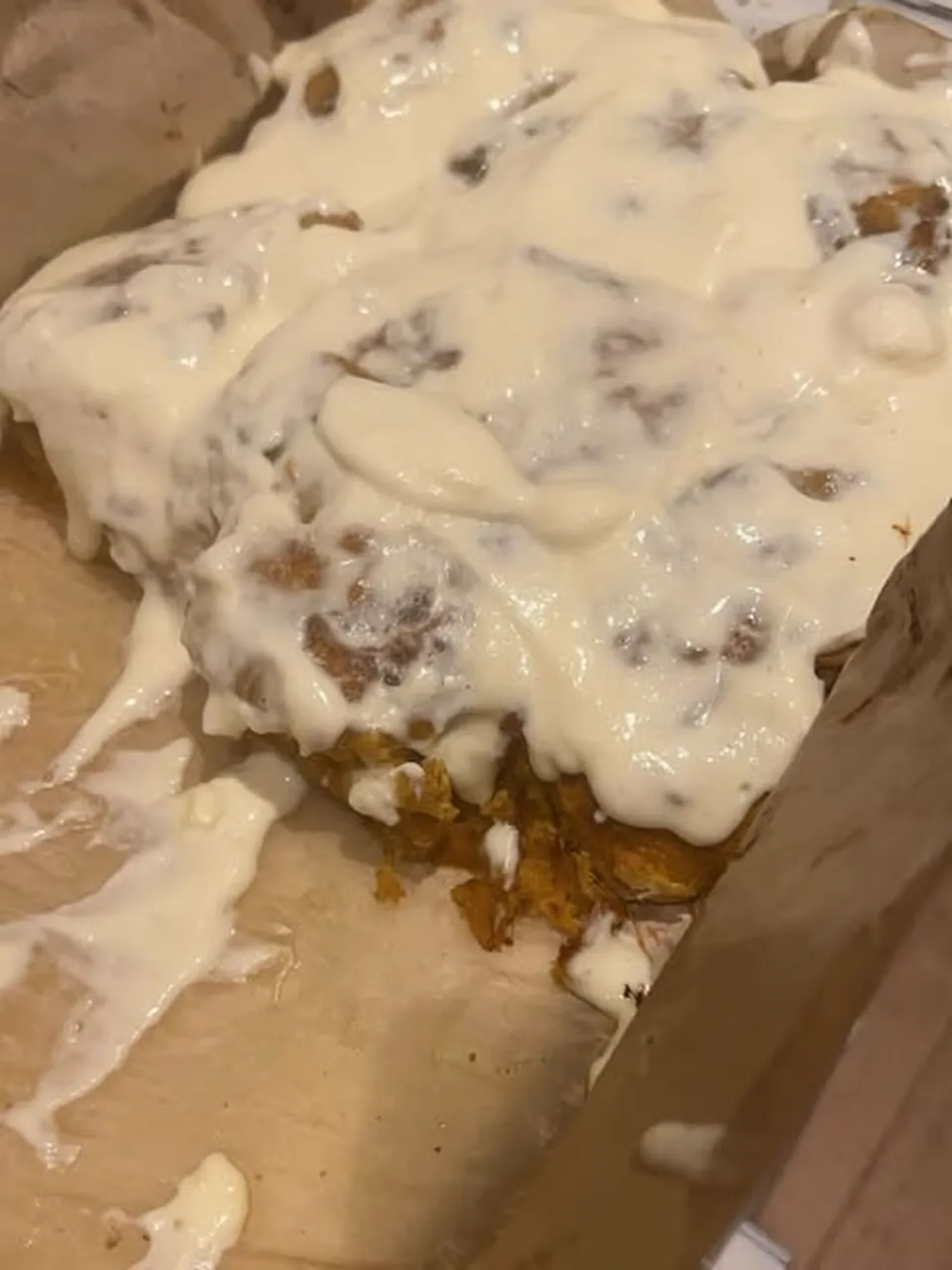 A tray of pumpkin cinnamon buns under a thick layer of cream cheese icing.