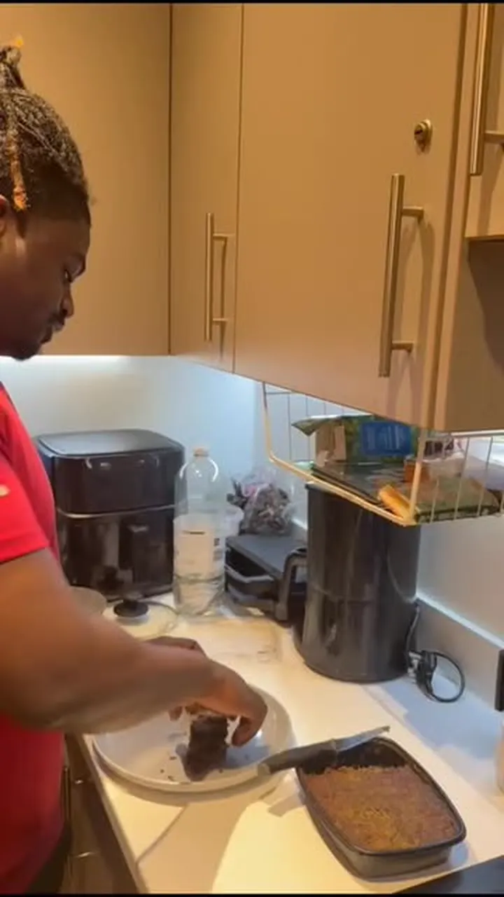 A baker slicing a tray of brownies on a kitchen worktop.